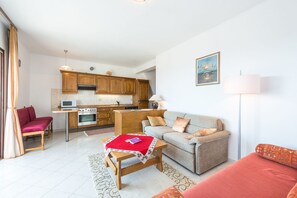 A compact living space with a kitchenette, a sofa, a dining table, and a red chair. - PENDO 1 apartment with sea view, near beach (Mlini)