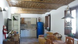 Une cuisine rustique avec un plafond en briques apparentes, un coin repas avec des meubles en bois et un réfrigérateur bleu.