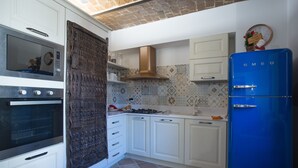 Une cuisine avec des meubles blancs, un réfrigérateur bleu et un crédence décorée de motifs.