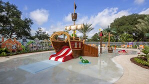 A pirate-themed water play area with a slide, a ship-shaped play structure, and a small green dinosaur figure.