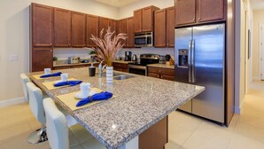 A modern kitchen with granite countertops, stainless steel appliances, and a central island with bar stools.