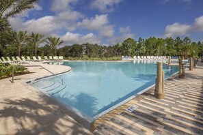 A swimming pool with lounge chairs and palm trees.