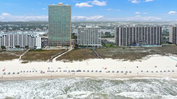 A beachfront hotel with multiple high-rise buildings, a sandy beach, and ocean waves. - Beachfront Gulf Condo! Renovated! Big Savings + Gorgeous Views! (Orange Beach)