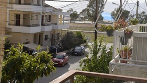 A residential street with two-story buildings, a parked red car, and potted plants on balconies. - 3 bedroom apartment in Nafplio (Nafplio)