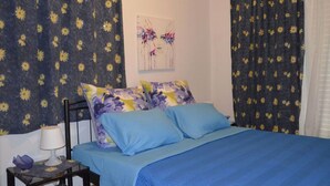 A bedroom with a bed, pillows, a nightstand, a lamp, and a painting on the wall. - 3 bedroom apartment in Nafplio (Nafplio)