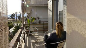 Un balcon avec une table, des chaises et un pot de fleurs.