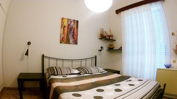 Une chambre à coucher comprenant un lit, une table de chevet, une étagère murale décorative et une fenêtre avec des rideaux.