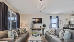 En moderne stue med to grå sofaer, et hvidt sofabord og en lysekrone.