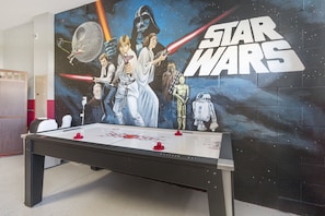 A Star Wars-themed room with a pool table and a mural of Star Wars characters.