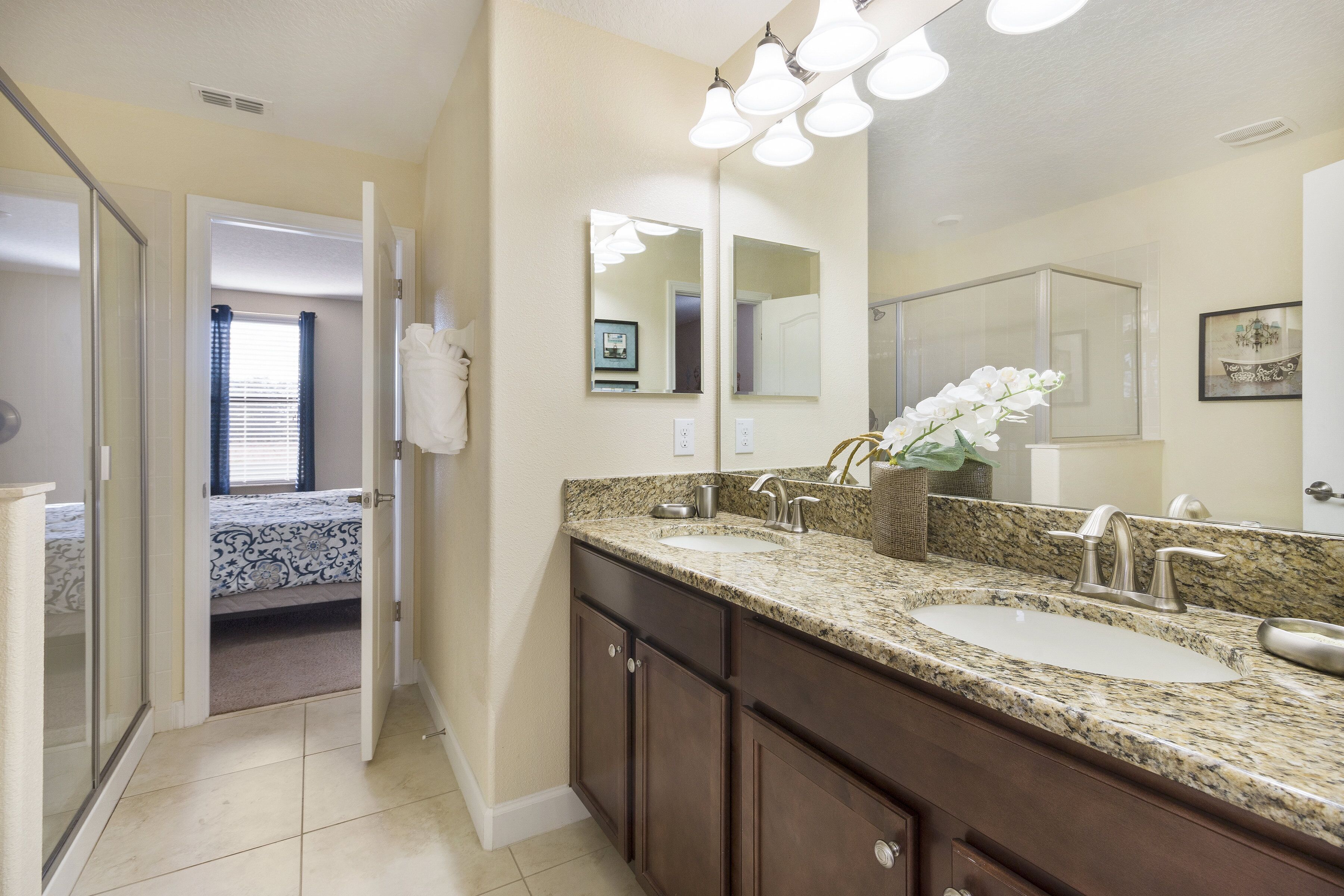 A bathroom with a double sink, dark wooden cabinets, a large mirror, and a shower with a glass door.