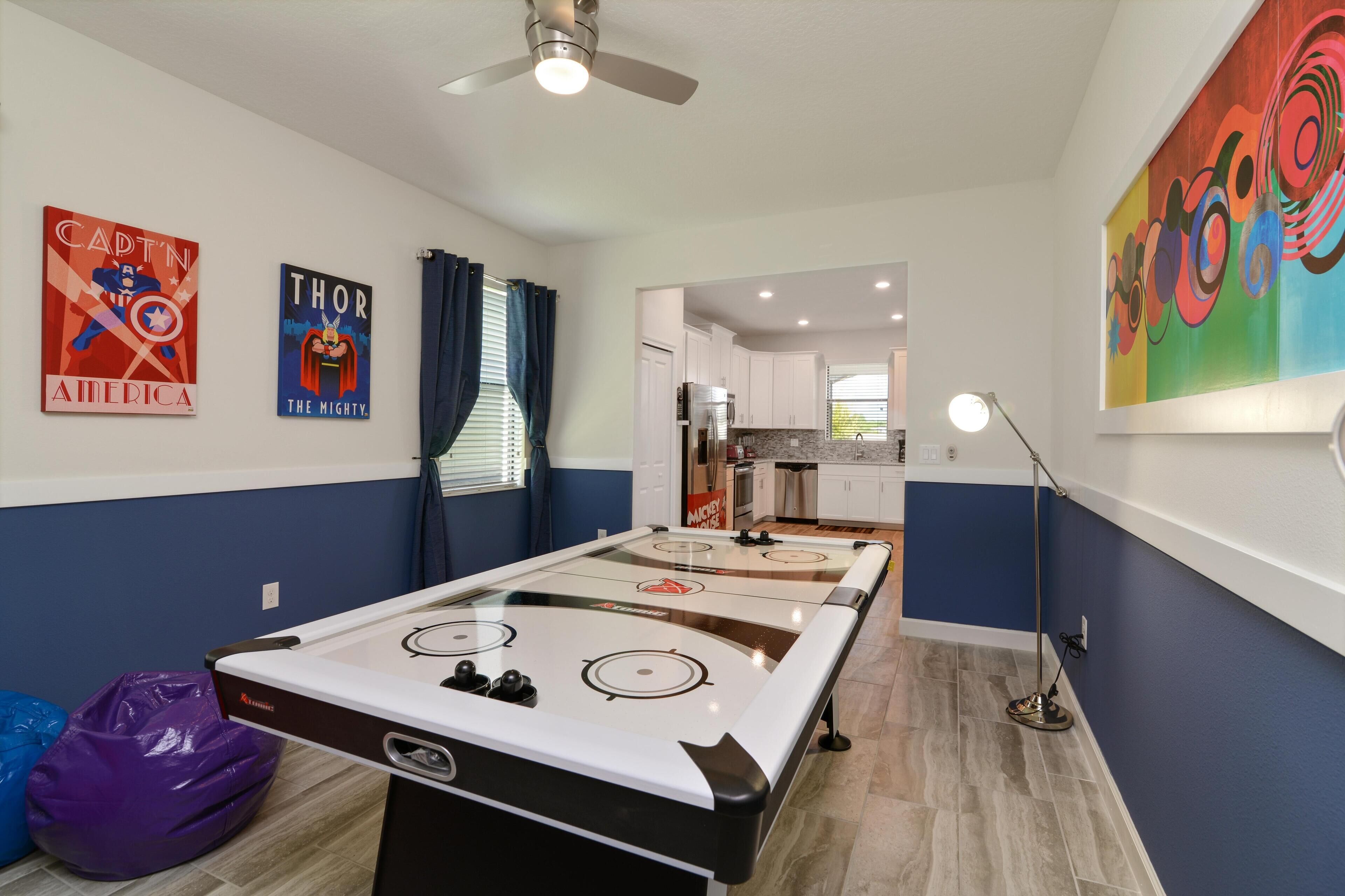 A room with a pool table, ceiling fan, and artwork on the walls.
