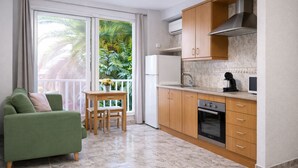 Une cuisine compacte avec des meubles en bois, un four encastré et une fenêtre donnant sur un paysage verdoyant.