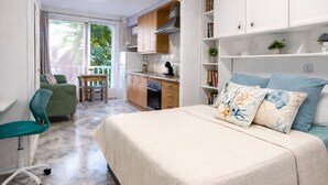 Une chambre comprenant un lit, un bureau, une chaise et un coin cuisine.
