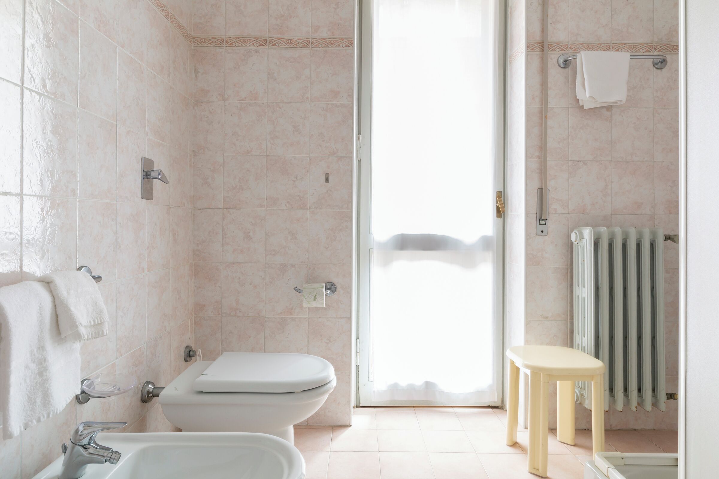 Un baño con inodoro, lavabo, ducha y toallero.