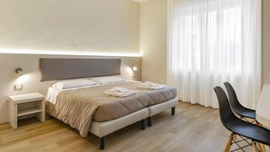 Ein modernes Schlafzimmer mit einem großen Bett, Nachttischen und einem Sessel.