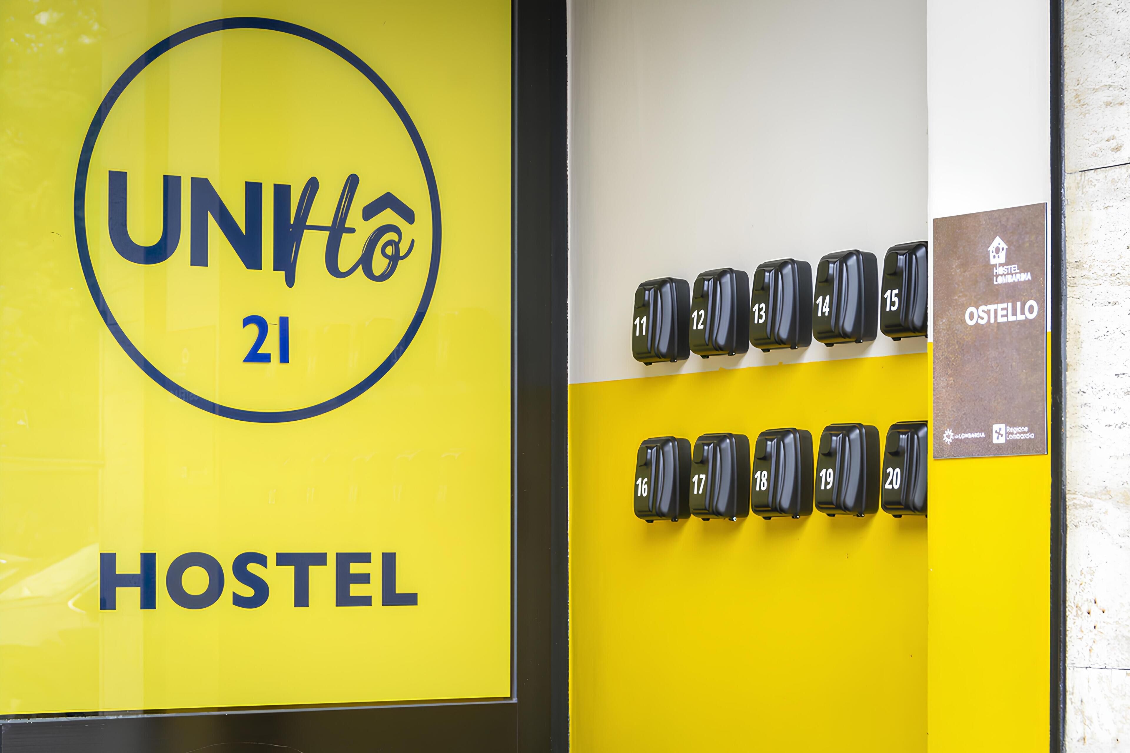Un cartel de hostal con el nombre "UNHto 21 HOSTEL" y una fila de maletas numeradas que indican los números de habitación.
