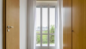 Ein Zimmer mit Holztür, einer Schiebetür zum Balkon und einem Teppichboden.