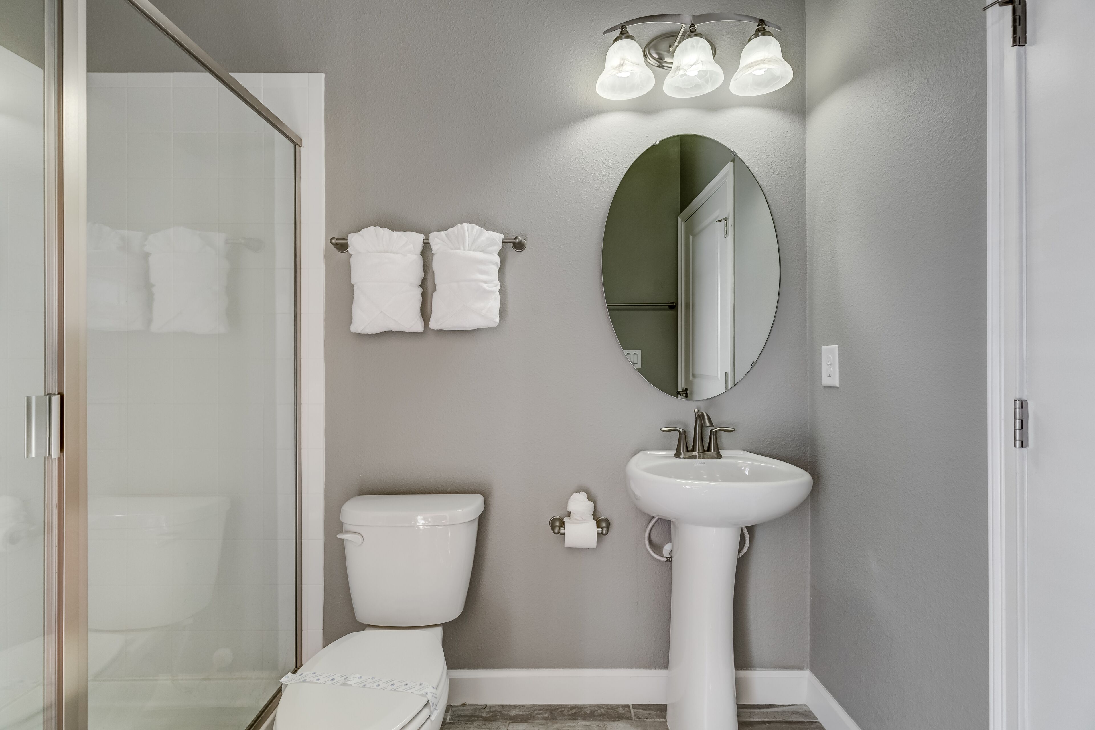 A bathroom with a toilet, sink, and shower. There are two towels hanging on a rack.