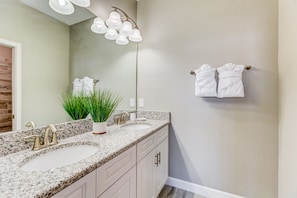 A bathroom with two sinks, a mirror, a towel rack, and a plant.