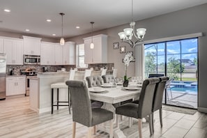 Enjoy a spacious kitchen with an island, dining area, and sliding glass door to a backyard with a pool.