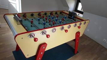 Une table de baby-foot dans une pièce dont le sol est en bois et dont le plafond est incliné.