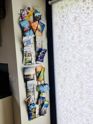 A wall with a collection of brochures and magazines, likely for a hotel or similar establishment. - Un Figuier Dans Notre Jardin (Beaune-la-Rolande)