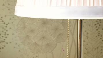 A lamp with a white shade and a hanging ornament.