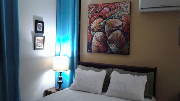Een hotelkamer met een bed, een lamp, een schilderij en een foto aan de muur.