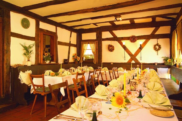 A dining area with wooden beams, white walls, and tables set for a meal. - Hotel Restaurant Zum Nachtwächter (Muehlacker)