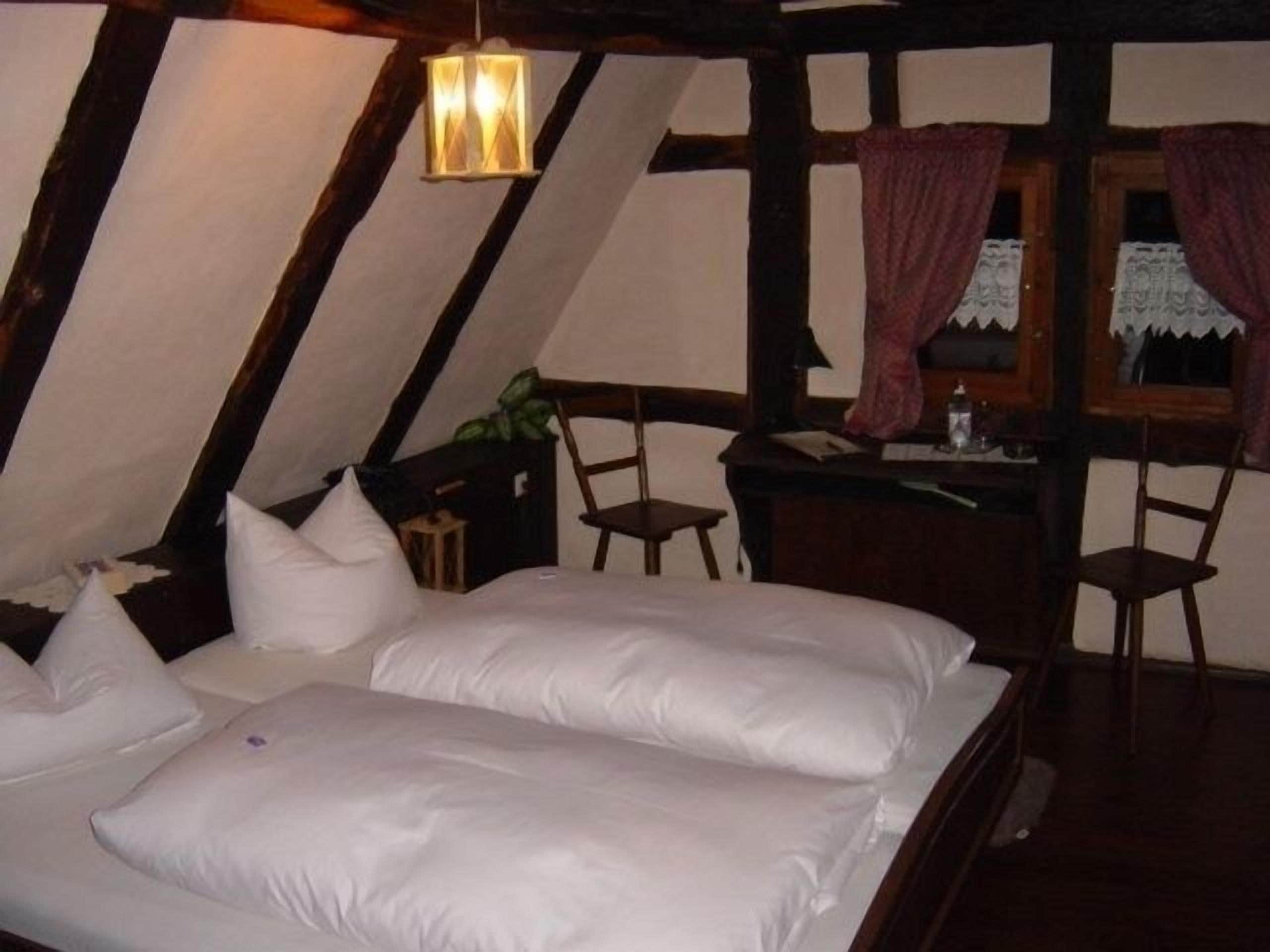 Quarto com uma cama grande, uma escrivaninha e um lustre.