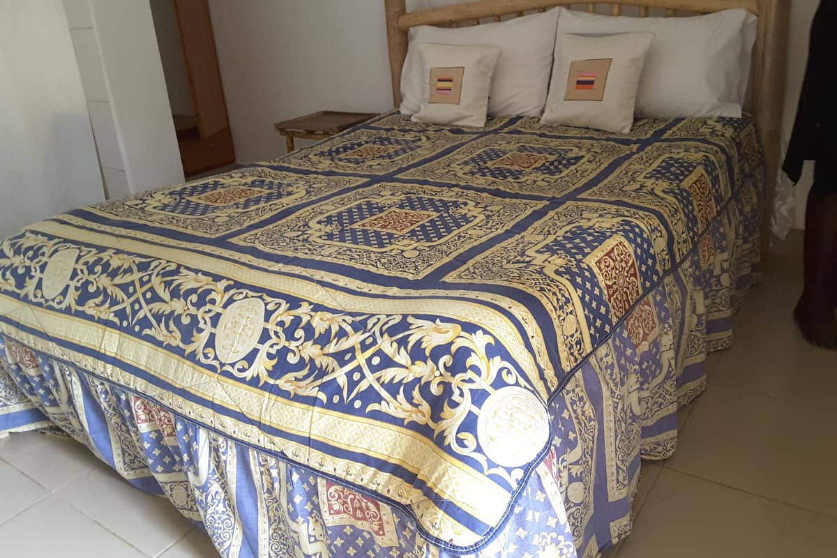 Una cama con una colcha estampada, un cabecero de madera y dos almohadas con parches bordados.