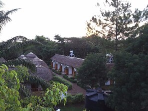 A rural setting with thatched-roof huts, surrounded by dense greenery and trees.