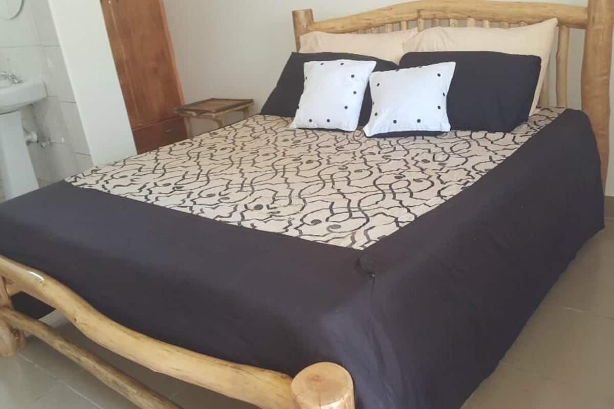 Una cama con colcha estampada, cabecera de madera y dos almohadas.