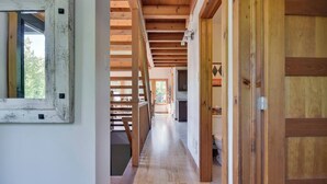 A wooden hallway with a staircase, wooden doors, and a view into a room with a window. - Dreaming unit near Le Massif (Petite-Rivière-Saint-François)