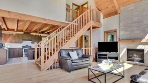 A spacious living area with a wooden staircase, a fireplace, a television, and a sofa. - Dreaming unit near Le Massif (Petite-Rivière-Saint-François)