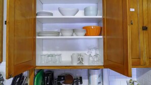 Uma cozinha com armários de madeira, prateleiras com louças e utensílios de cozinha.