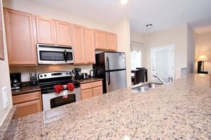 A kitchen with granite countertops, stainless steel appliances, wooden cabinets, and a double sink.