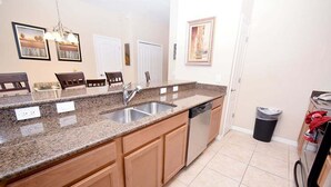 A kitchen with granite countertops, stainless steel appliances, wooden cabinets, and a trash can. - Dog-Friendly · Dual Masters · Private Pool · Resort Amenities · Near Disney (Kissimmee)