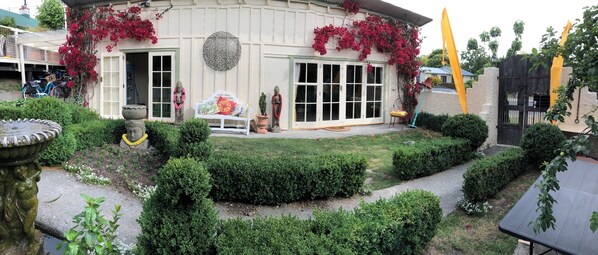 A traditional building with a garden, a white bench, and a statue.