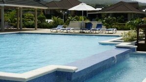 A swimming pool with blue tiled edges, lounge chairs, and umbrellas. - Artscape Jamaica Villa @Richmond near Ocho Rios (Priory)