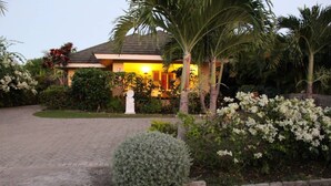 A house with a paved driveway, surrounded by various plants and a palm tree. - Artscape Jamaica Villa @Richmond near Ocho Rios (Priory)