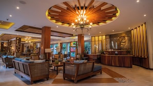 A spacious lobby with wooden furniture, a central chandelier, and a reception desk. - La Jolla Beach Resort (Bagac)