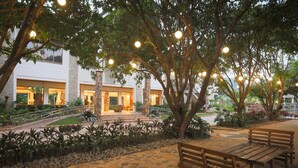 An outdoor patio area with stone flooring, wooden benches, and hanging lights. - La Jolla Beach Resort (Bagac)