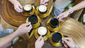 A group of people holding coffee cups around a wooden table.