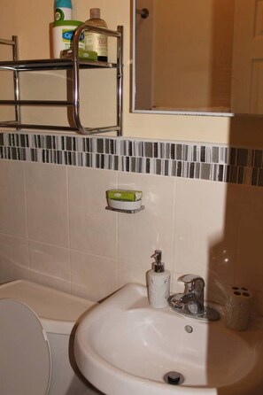 A bathroom with a white sink, a mirror, and a towel rack.