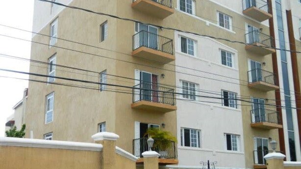 A multi-story residential building with balconies, a gated entrance, and a beige exterior. - The Artist Place @ Kensington New Kingston (New Kingston)