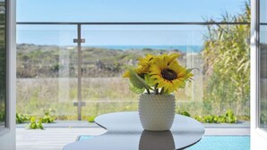 Une pièce moderne avec une grande fenêtre, une table ronde et un vase rempli de tournesols.