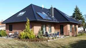 A two-story house with a sloped roof, solar panels, and a brick exterior. - Apartment Hiddensee (Wiek)