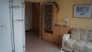 A living room with a sofa, a cabinet, a clock, and a painting on the wall. - Apartment Hiddensee (Wiek)