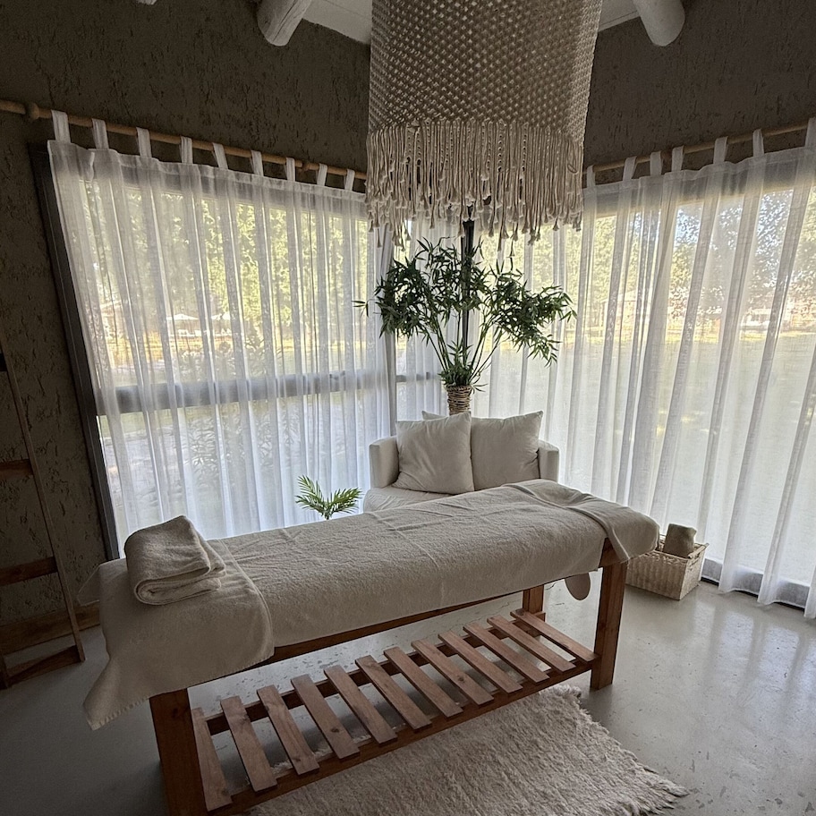 A room with a wooden bench, a hanging light fixture, a potted plant, and sheer curtains.
